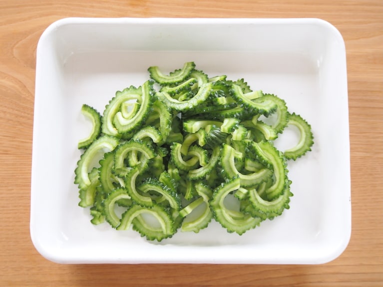 ゴーヤは縦半分に切り、スプーンで中のわたを取り除く。5mmほどの厚さに切る。