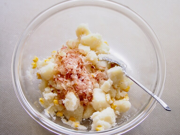 串が刺さるくらいの固さになったら、ザルで湯切りをする。じゃがいもの水分がとんだらボウルに入れ、ホールコーン缶、鰹節、塩胡椒を熱いうちに入れてよくかき混ぜる。