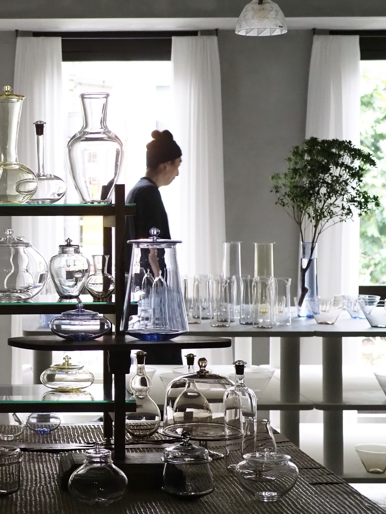 個展初日のオープン5分前。まだ照明を点けていないので、ガラスのうつわたちは窓からの逆光で静かに佇んでいます。私の好きな光景。うしろに写っているのは作家の永木卓さん。長身でイケメンなのですが、まもなく個展がはじまるという緊張感で、ちょっぴり猫背気味になっているのが可笑しい。初日には作家が在廊していることが多く、作った本人とお話できる貴重な機会です。ぜひ気軽に声をかけてみてください。