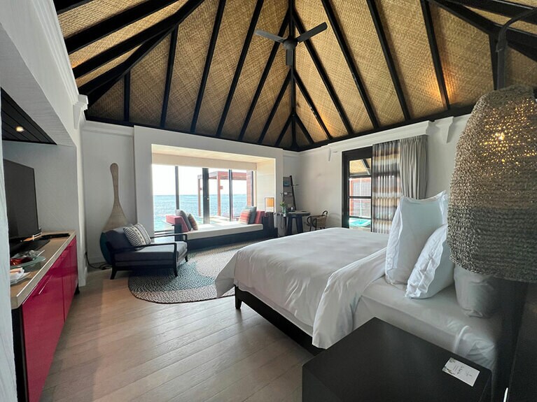 水上バンガローの室内。ベッドは海に向かって配されている。天井が高くて開放的。