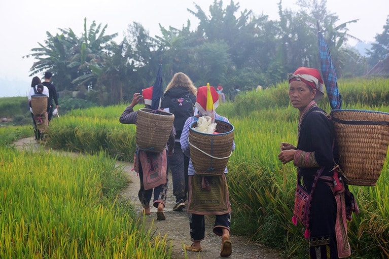 ハイキングの一群をすり抜けて、あぜ道をゆく赤ザオ族。