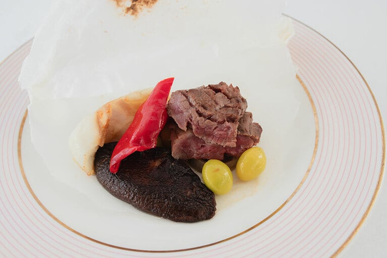 「熊野牛とクエの紙包焼」。包みを開くと隠し味のブルーチーズが香る。