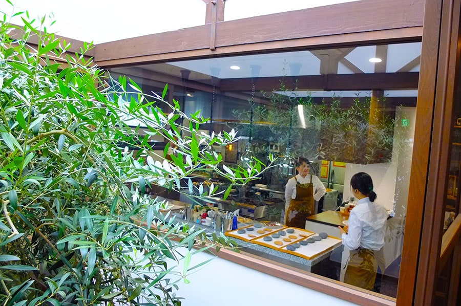 ［SHÓKUDŌ YArn］オリーブの木が茂った中庭を望むかわいいキッチン。ここからどんなお料理が運ばれてくるのか、期待に胸がふくらみます。