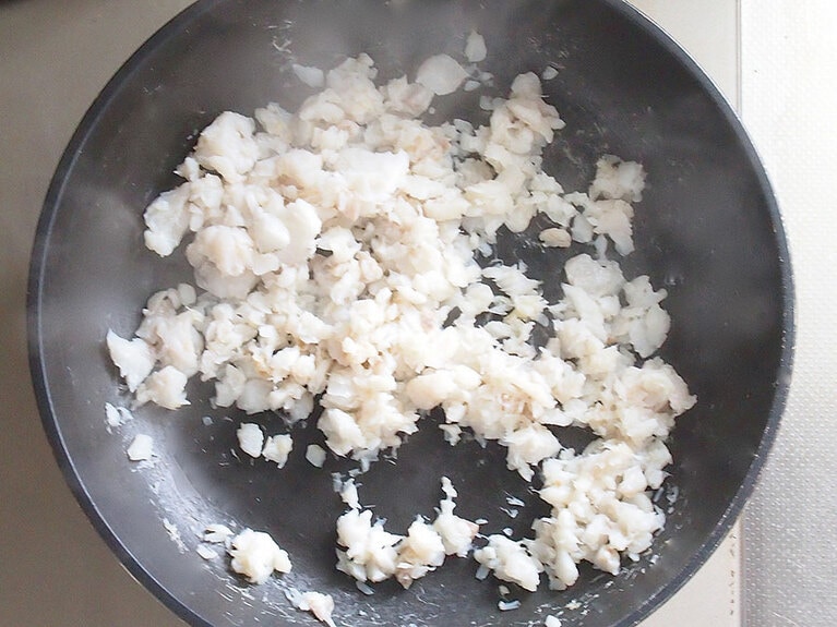 タラを、木べらで細かく潰すように炒める。