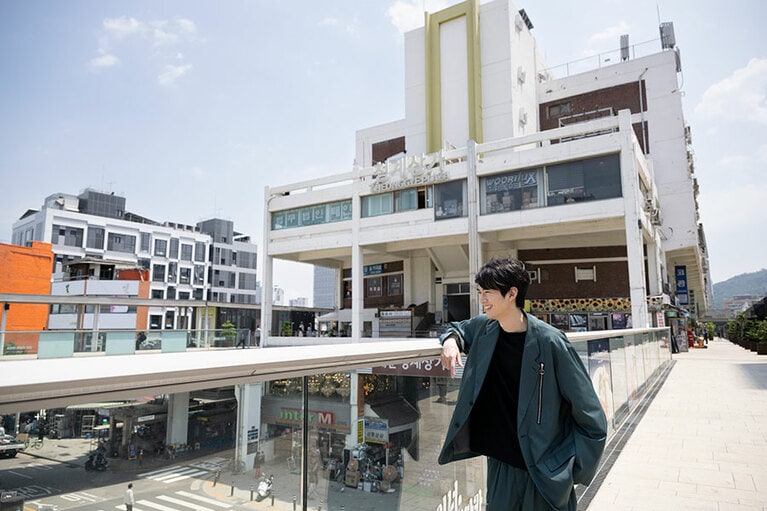 ドラマ「ヴィンチェンツォ」第2話で、ヴィンチェンツォが広場で行われたワインパーティーを見下ろす場面を再現する和田さん。