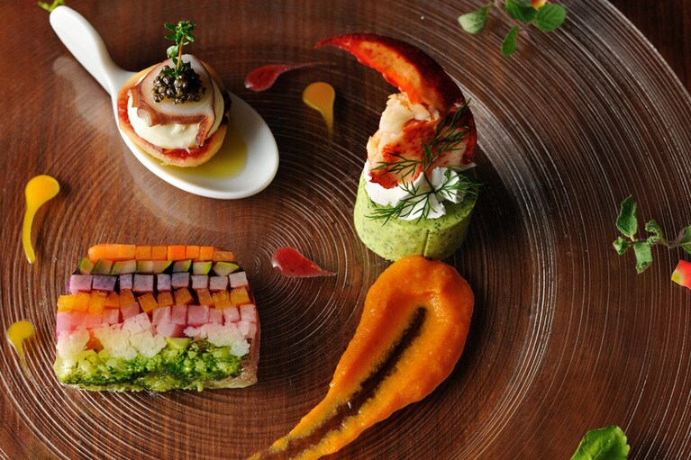 レストラン「アリア」では、地元食材も取り入れたフランス料理を。ディナーの一皿「7種の野菜テリーヌ オマール海老とイチジク」。