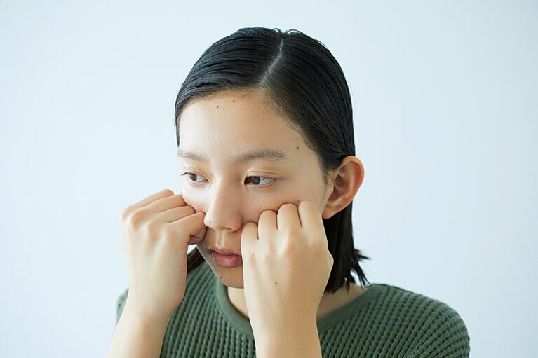 STEP2 頰をグッと押し上げる。両手をグーの形にして、小指が小鼻の横にくる位置に置く。頰骨を押し上げるように圧迫しながら、耳の前まで手を移動。これを3回繰り返す。