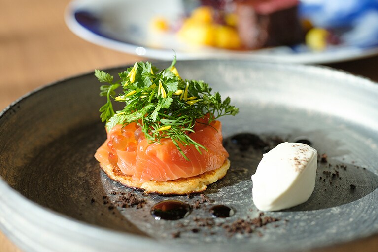 石巻産の銀鮭を使ったサーモンマリネや自家製イクラ、蔵王ハーブをジャガイモのパンケーキに合わせた前菜･銀鮭のブリニ。宮城県産の魚介を中心に東北の旬魚がいただける「グリーチネ」のコースは、ランチ 2,500円(4品)～、ディナー 3,500円(5品)～。