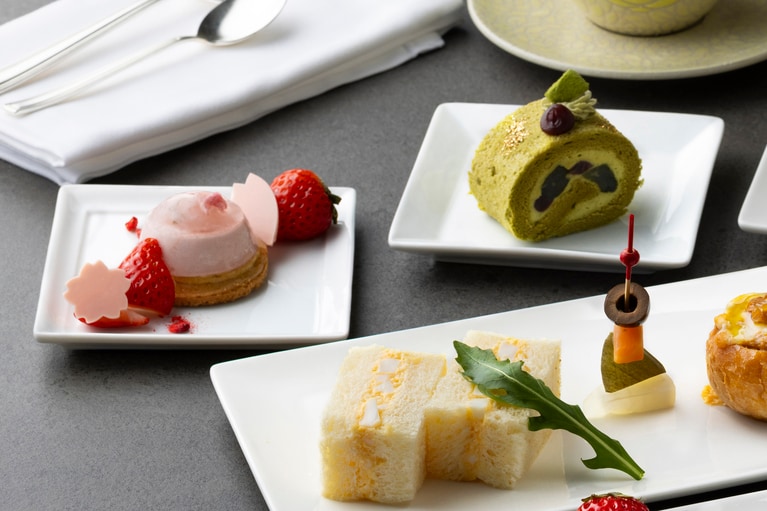 写真左は、甘じょっぱい味わいのアクセントに、桜の花びらを模したチョコレートを添えた「桜といちごのムース」。セイボリーには、人気の「卵サンド」と、スパイス香る「キーマカリーのミニパングラタン」なども付いて、ボリューム満点だ。