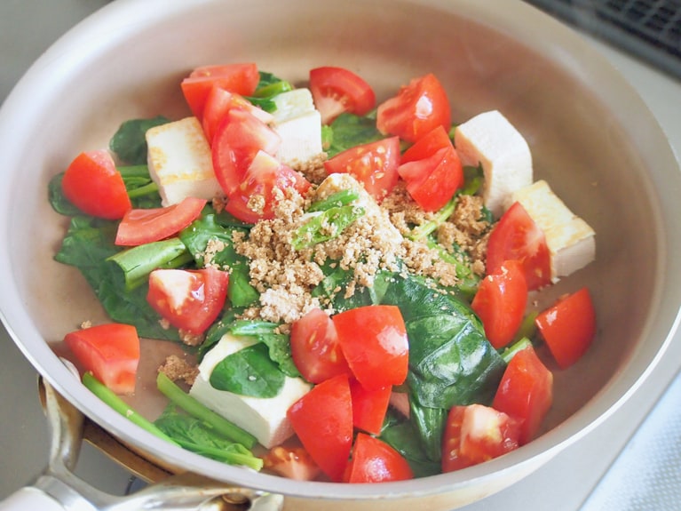 （1）のトマト、（2）の水気をきったほうれん草、（3）の豆腐を入れ、全体をよく混ぜる。ほうれん草がしんなりしてきたら、（4）の調味料を入れる。