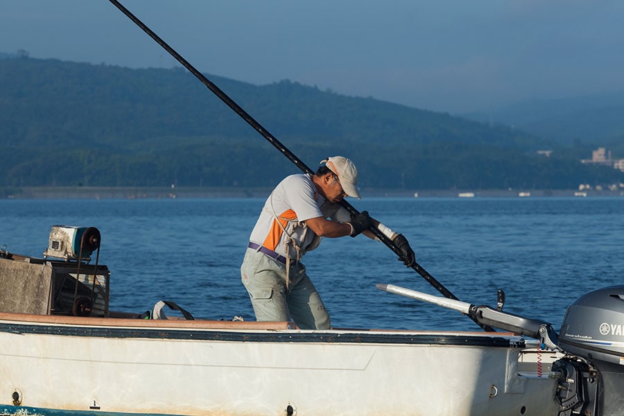 手掻きでしじみ漁を行う漁師さん。保護のために操業日や時間、量が決められています。写真／宍道湖漁業協同組合
