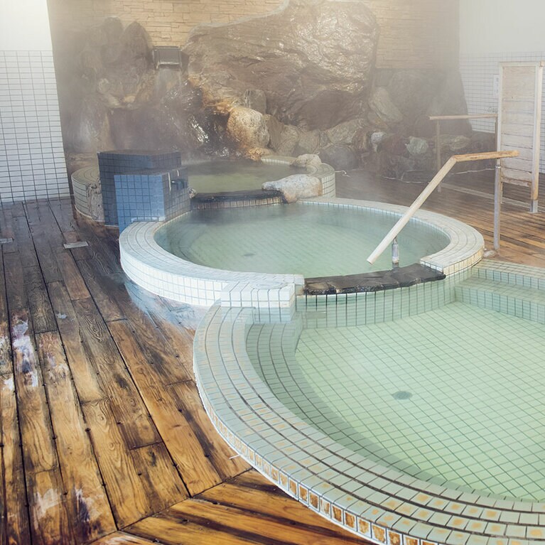 #銭湯も源泉掛け流し／加熱加水をしていない、源泉掛け流しの鹿児島市内の銭湯「みょうばんの湯」。少しとろみのある泉質は保温性も抜群で飲泉も可能。冷え性に効くのはもちろん、美肌効果も期待できるとか。檜張りの床に湯温が2℃ずつ異なる三段浴槽と、珍しいつくりの浴室の風情も楽しみたい。