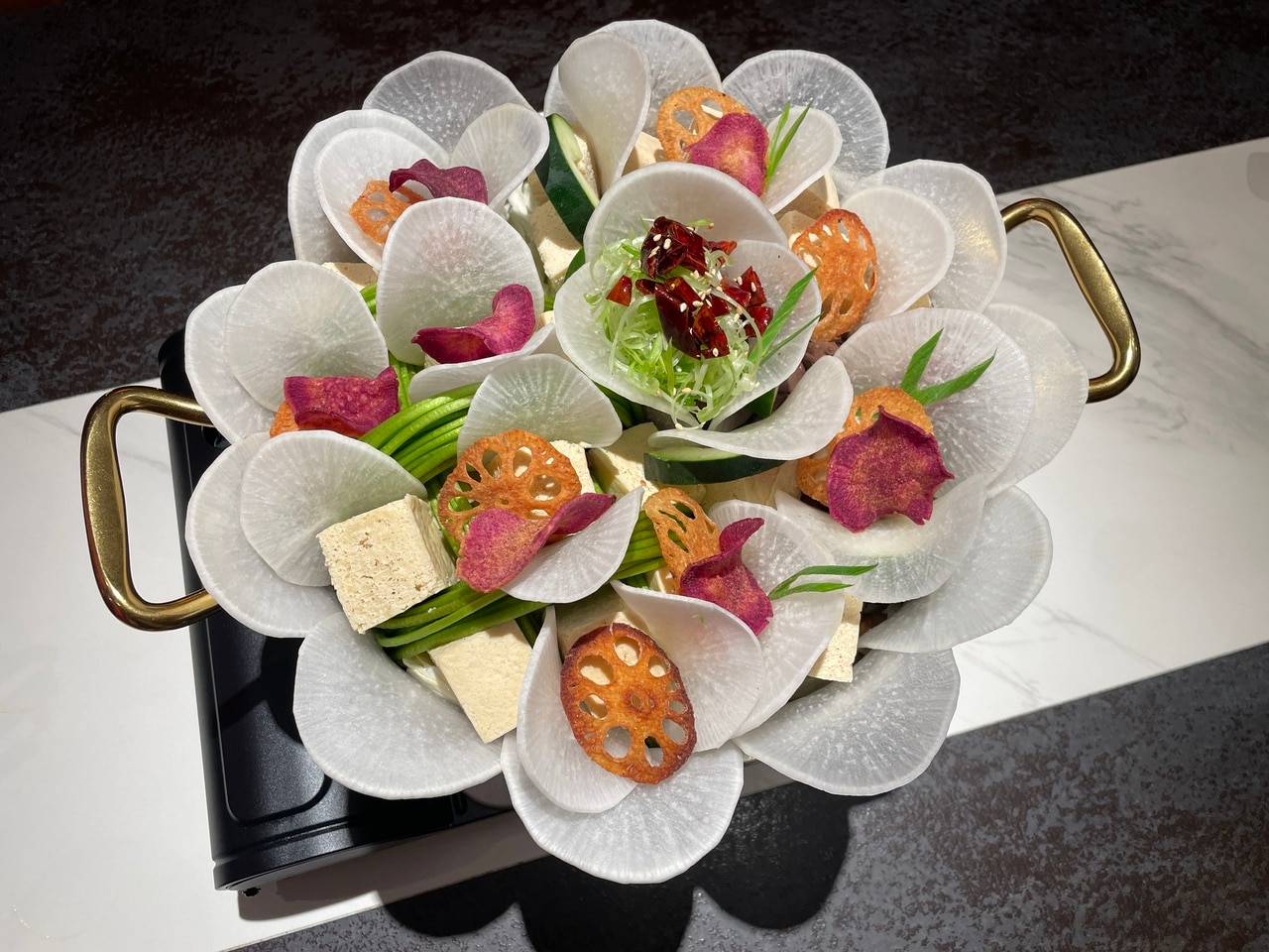 花が咲いたように美しく盛りつけられた具材。レンコンや紅芋チップスはそのまま食べられるので、鍋が仕上がるのを待ちながらどうぞ。