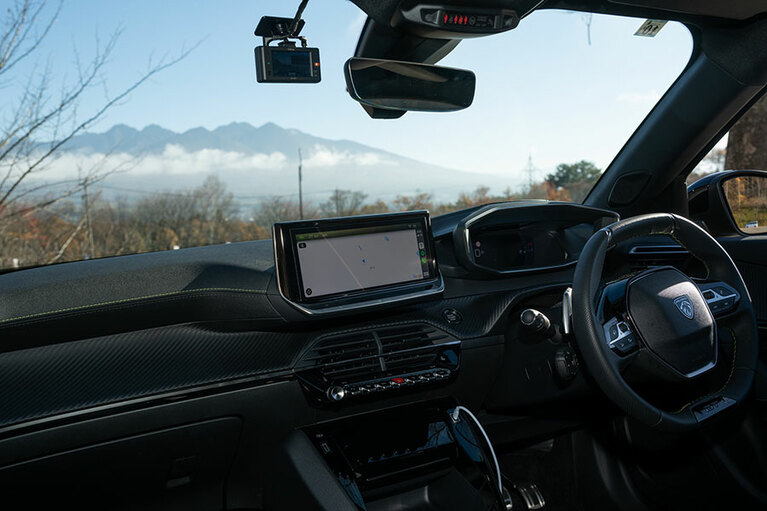 フロントガラスにくっきり映る八ヶ岳。今日は絶好の登山日和だ。新型プジョーのステアリングホイールはコンパクトで女性でも運転しやすく、大画面のセンサータッチスクリーンも便利。