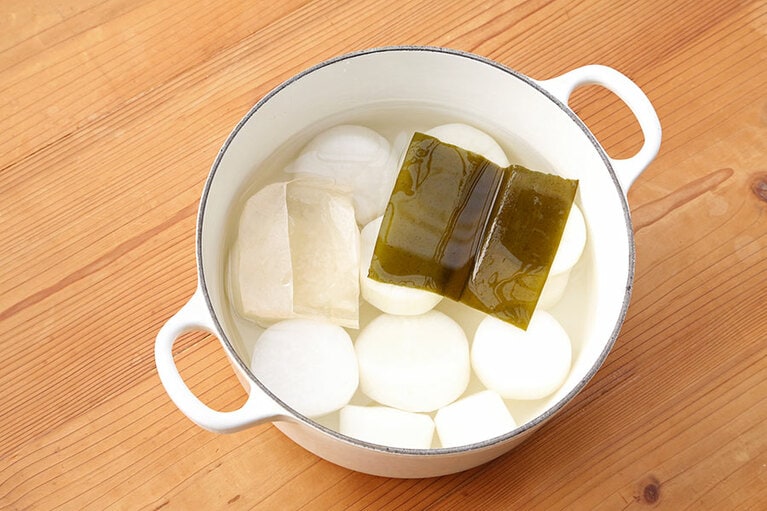 鍋に大根を並べ入れ、市販のお茶パックに入れた米、昆布を入れて水を注ぎ火にかけ沸騰後に弱火にして40～50分煮る。