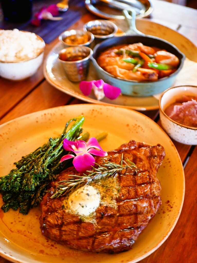 「ハウス ウィズアウト ア キー」で楽しき夕食。手前はリブアイステーキ（58ドル）、しつこくない上質なコクに満ちている。奥はピントが合ってなくて申し訳ないが、ハワイ産キアヴェの木でスモークしたチキンのココナッツカレー（38ドル）で、ココナッツミルクが濃厚でたまらないおいしさ、パイナップルのチャツネが絶妙に合う。