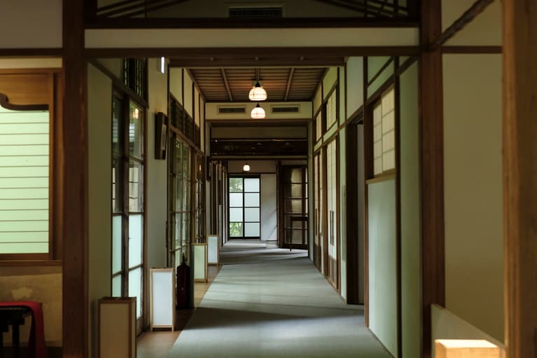 一枚一枚手作りされた、ゆらぎのある「大正硝子」から入る上品な光に包まれた廊下。歴史の重みを感じる静謐な佇まいに自然と背筋がのびる。
