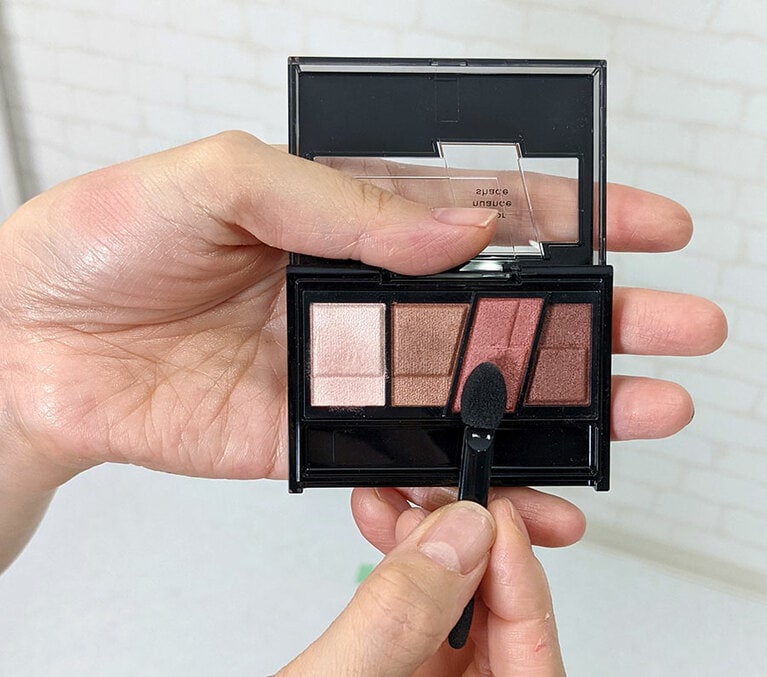 右から2番目と左端のカラーをチップに取り、手の甲で混ぜてからアイホール全体より広めに入れる。