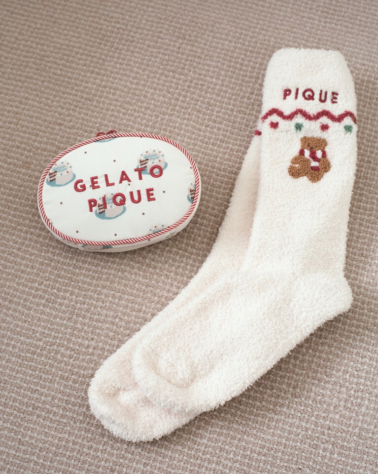 マフラーを巻いたベアが刺繍されたルームソックスはプチギフトに。赤いロゴが印象的なケーキの総柄ポーチはダブルファスナーで内ポケット付きなのでマルチに使える。（左）オーバルポーチ 4,950円、（右）さがらBEARソックス 3,960円。