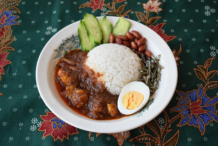 ご飯、温めたチキンサンバル、付属の煮干しとピーナッツを盛り付け。そこにゆで卵ときゅうりを別途加えればナシレマッの完成。