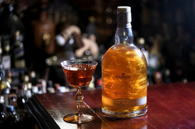 THE BLACKSMITH。イル・ド・レ ファインアイランドの深みがカンパリ、グレープフルーツ、メスカルなど多彩な味をしっかり支えます。カミュの瓶の中でクルクル踊る金粉が幻想的。