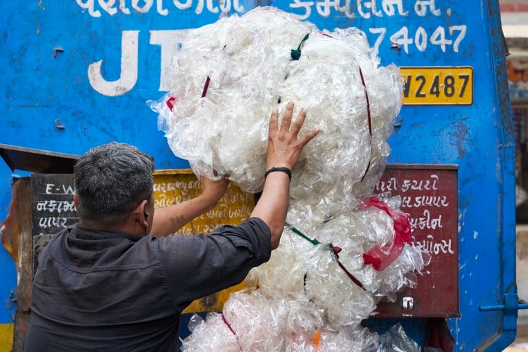 プラスチックを使用したゴミ袋を専用リサイクルトラックに詰め込む人々。プラスチックのゴミ問題は世界中に広がる。インド・スーラトの路上で。© Rolex/Greg White