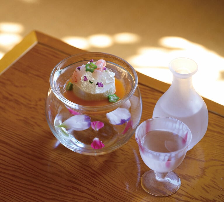 花びらをあしらった前菜。トマトウォーターのジュレと甘エビの昆布締めをのせ、ビスクソースでいただく「佐渡産の根菜のムース」。