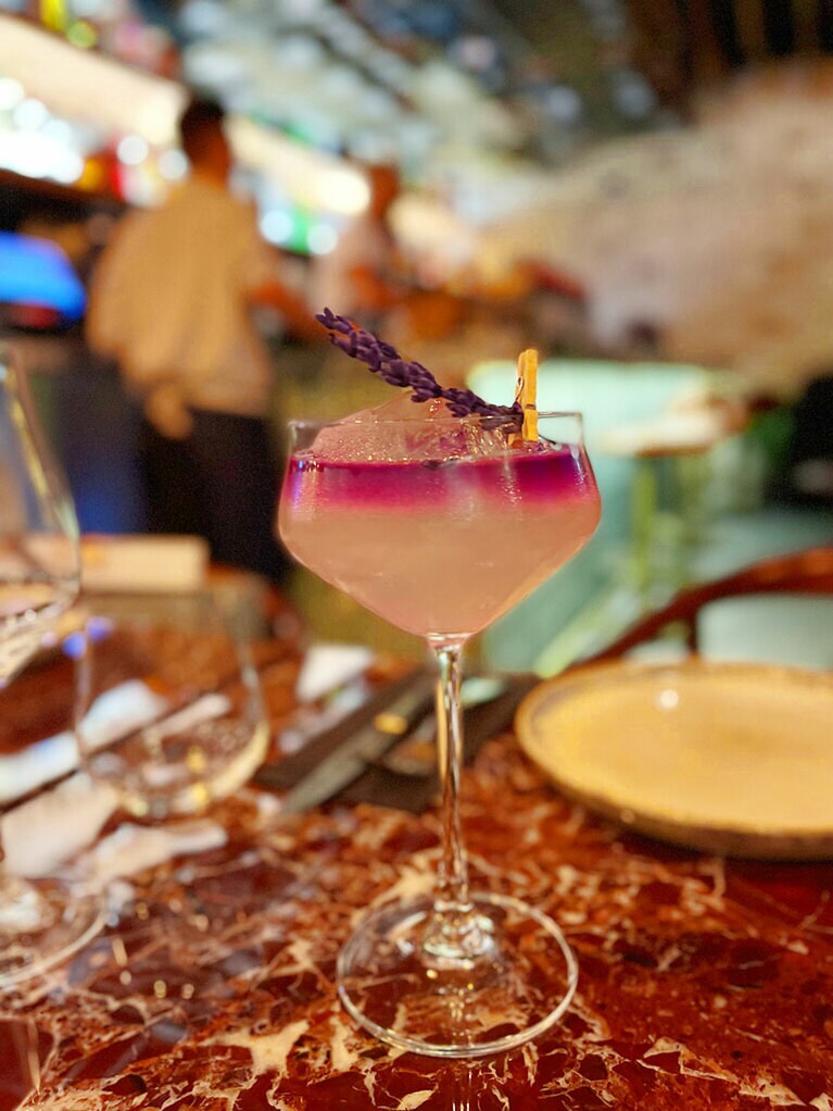 シトラスとピーチをベースに、ラベンダーなど花の香りを添えて、目の前で紫のバタフライピーのリキュールを注いでくれる。ラベンダーの花飾りもフォトジェニック！