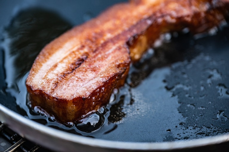 燻し上げベーコンはブロックのまま両面をこんがりと焼いたら、お好みの厚さにカット。夜にお酒と合わせても、朝にごはんのおともにしても。