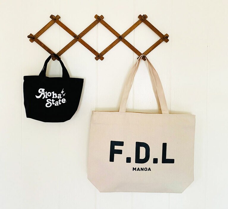 The Fanon はアップロールカフェで購入可能。黒スモールトート 22ドル。白ジッパートート 28ドル。