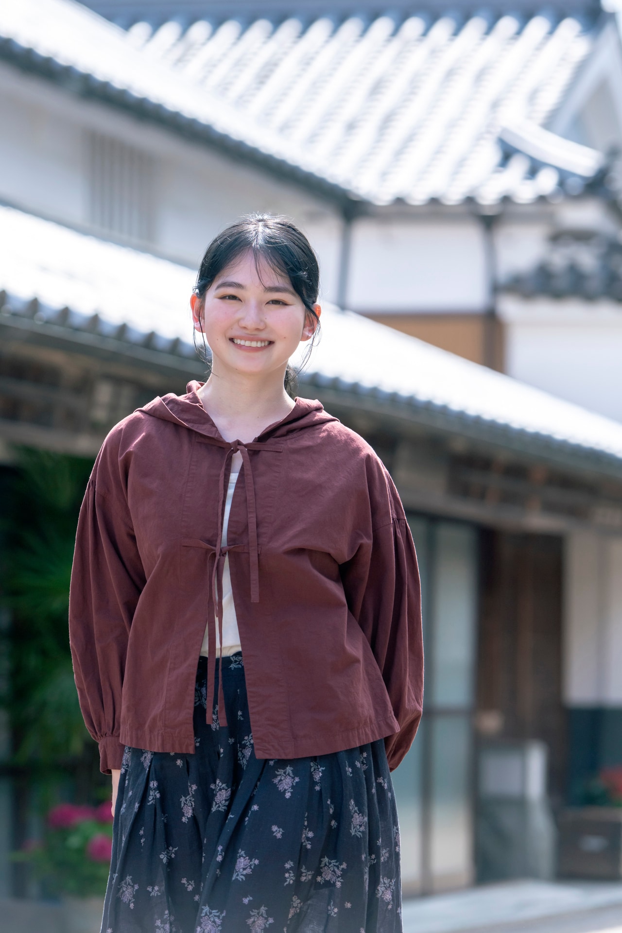 ネストローブの秋の新作をまとった山田さん。フロントに配したリボンを結ぶ、コットンとリネンの生地のフーディーは軽やかで通気性もよい。気温が不安定な秋口にさらりと羽織りたい。山田さん着用：コットンリネン超撥水リボンフーディー（BRICK）／28,600円、フラワープリントタックスカート（柄）／36,300円（税込、9月下旬発売予定）
