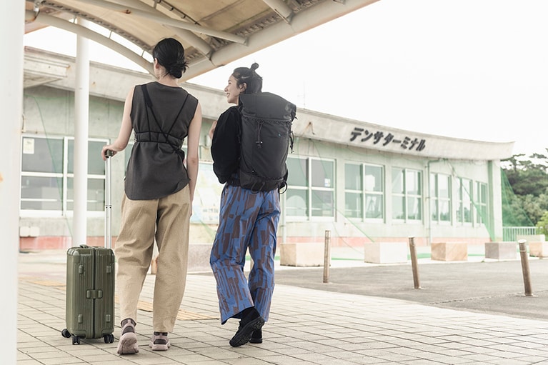 【サンダル以外の衣装】左：サコッシュ［ハーベスト マテリアル モジュラー トラベル ポーチ Fawn/Birch］ 3,520円／キーン(キーン・ジャパン)、キャミソール19,800円、パンツ 34,100円／ともにフミエタナカ（ドール 03-4361-8240）、スーツケース 参考商品／リモワ（リモワ クライアントサービス 03-4571-1319）、その他／スタイリスト私物。
右：サコッシュ［ハーベスト マテリアル モジュラー トラベル ポーチ White/Black］3,520円／キーン(キーン・ジャパン)、ブラウス 34,100円／フミエタナカ（ドール 03-4361-8240）、パンツ31,900円／フィーニー（フィーニー 03-6407-8503）、その他／スタイリスト私物。