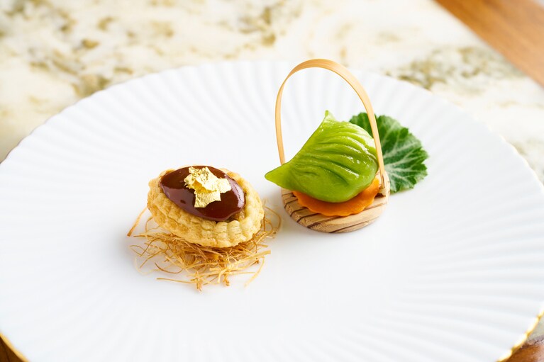 点心は「鮑のオイスターソース煮込み 葱とマッシュルーム入りナマコパイ」と「久米島産車海老と空豆の蒸し餃子」。小室シェフによる繊細なプレゼンテーション。