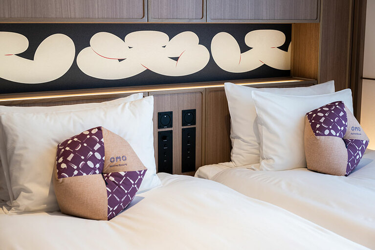 寄席の「大入」がモチーフのヘッドボードや、工芸品や職人の使う道具が描かれたクッションなど、ディテールにこだわりを感じられる。クッションの柄に招き猫を発見したらラッキーなのだとか。