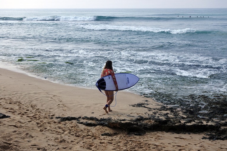 波を見定めて、さっそうと海へ向かう女性サーファー。