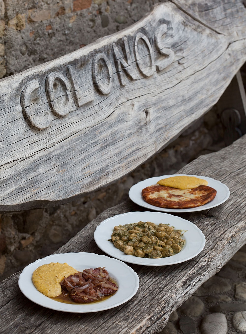 中庭のベンチで。COLONOSの店名入りなのは、アートイベントをした時にアーティストが作ってくれたから。写真手前“ヴィネガー風味のサラミ ポレンタ添え”(6.50ユーロ)は人気メニュー。