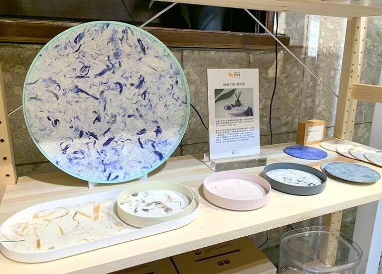 植物や木屑などの生命を永遠にプレスしている器。サイズや形は色々あります。右端はコースター。纖維木器-圓托盤(丸いお盆) 690元(小)、2,180元(大)、纖維木器-長托盤(長いお盆) 1,430元～、纖維木器 杯墊(コースター4枚組) 1,160元～。