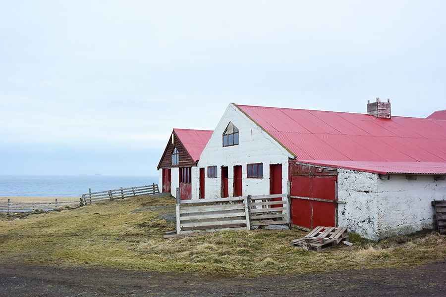 海を見晴らす丘の上に立つ厩舎。渋い色合いの中、赤い屋根が映える。