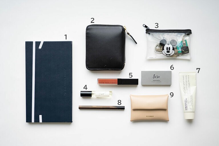 1：クリエイターズダイアリーを使い始めてから、1年間の仕事が可視化されるので見通しがつきやすくなりました。2：出産後は荷物を減らすために、長財布から小財布派に。飾らない形が気に入った「コムデギャルソン」を愛用。3：「鍵を探す時間を省くために小さなポーチにまとめています」。4：「バイレード」のロールオンの香水。5：マットに色づく「アディクション」のリップは私的名品。6、8：「ベースメイクが崩れてもアイブロウとアイラインが整っていればきちんと見える気がして」。「アンドビー」のアイブロウパレットと「メイベリン」のアイライナー。7：「ルラボ」のハンドクリームはヒノキの香り。出産前のように毎日つけるものではなくなってしまったけど、気分をあげたい時に肌にのせます。9：「ジルサンダー」の名刺入れ。明るいベージュと上品に艶めくスムースレザーが気に入り購入。