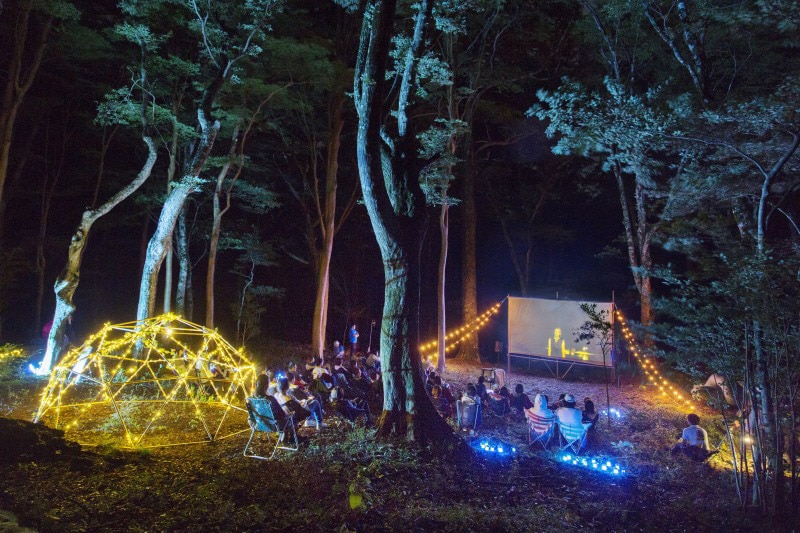 夜の森に1日限定で設えた特別な映画館がオープン。野外映画フェス「夜空と交差する森の映画祭」を手がけるサトウダイスケ氏のセレクトによる短編映画を上映する。