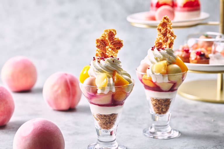 「Peach Melba Parfait（ピーチパフェ・メルバ）」のイメージ。19世紀後半にフランスのシェフ、オーギュスト・エスコフィエがオペラ歌手ネリー・メルバに捧げたといわれるクラシックデザート「ピーチ・メルバ」をもとに考案、グラスデザートパフェとして仕上げたられたひと品。