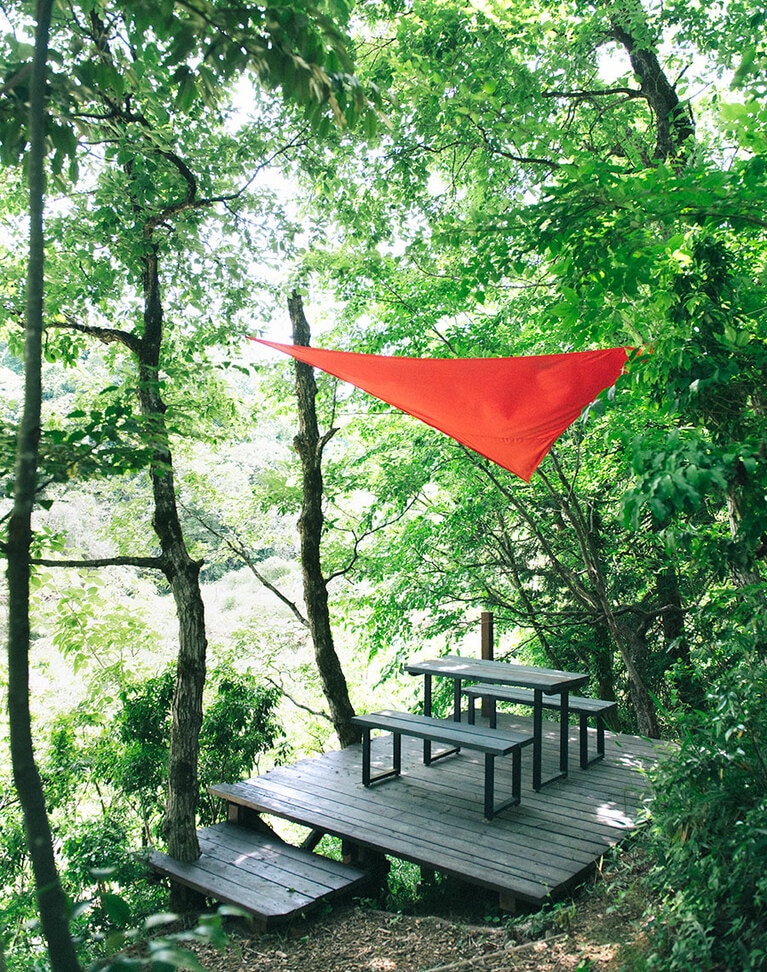 傾斜に建てられた森に浮かぶようなテーブル席。通り抜ける風が気持ちよい。