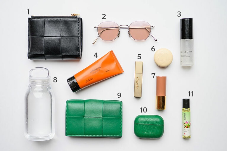 1、9：「ボッテガ・ヴェネタ」の財布と名刺入れは、2年前に新しいスタートを切るタイミングで購入。自分を鼓舞する意味を込めて。あえて対照的な色をセレクト。2：薄ピンクのカラーレンズサングラスは「ブラン」。軽くて薄いので持ち運びに◎。3：年中欠かせない「べリュマン」のハンドローション。ベタつかないのでPC作業中にも最適。4：ウッディな香りに惹かれた「フラマ」のハンドクリーム。目線の先にある手はいつも潤っていたい。5、6、7：リップケアは「スアビナ」のバームを愛用。カラーは、「セルヴォーク」と「リーカ」を。8：「キントー」のボトルは超軽量。10：AirPodsケース。毎日持ち歩くものはお気に入りのカラーを。「メゾンドサブレ」のもの。11：「ナリン」のカーミングロールオン。リラックスしたいときにくるくると。