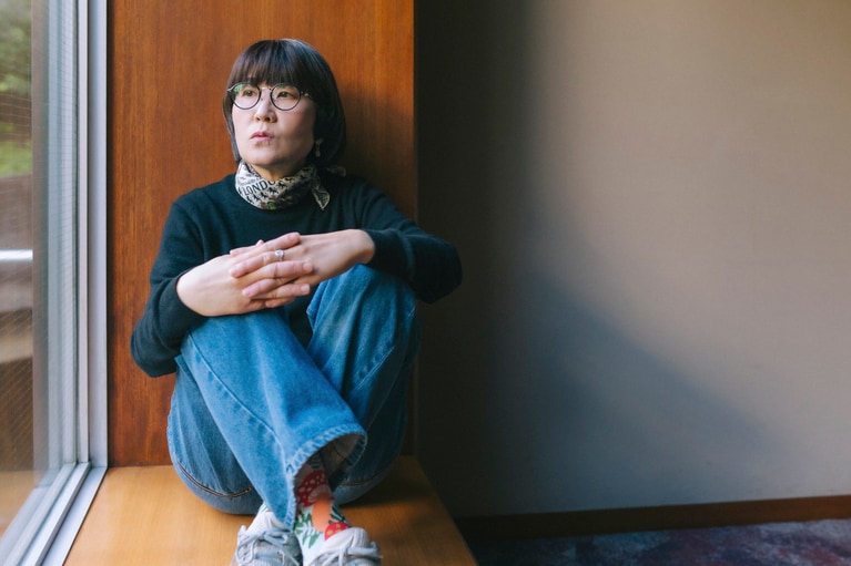 窓辺に座る光浦さん。