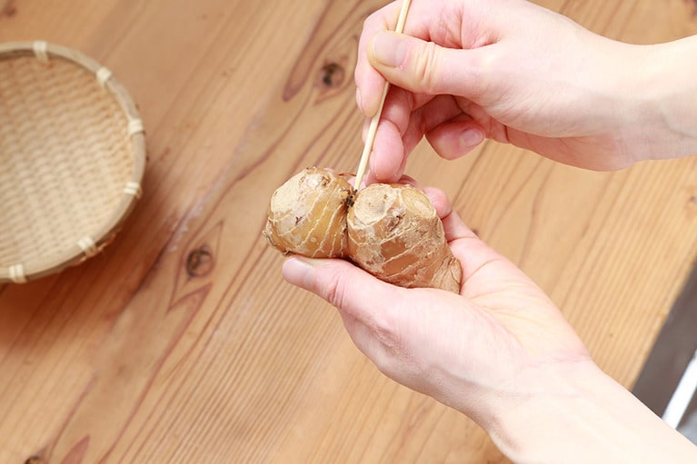 生姜は皮付きのままたわしで洗う。溝の部分は竹串を使って泥をかき出すと良い。