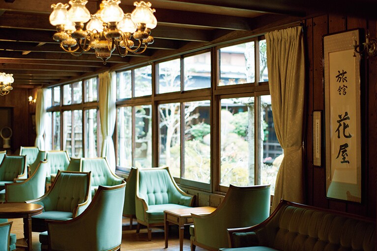 【旅館花屋】中庭を望むロビー。4代目の当主が「マルニ木工」で揃えたという味わいの出た調度品が、いっそうのときめきを醸す。Photo: Masahiro Sanbe