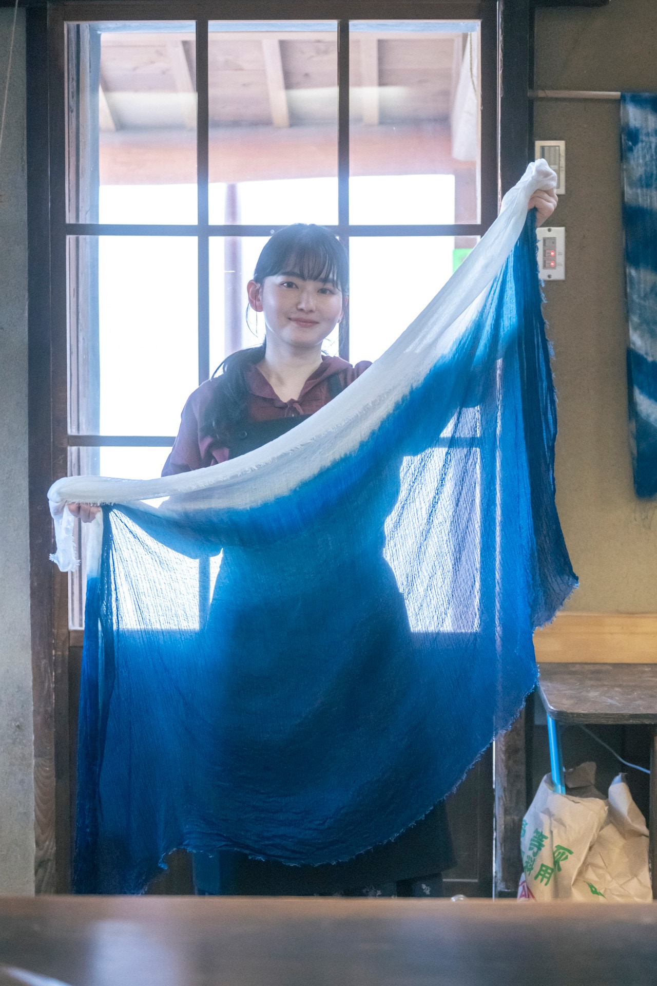 小学校ぶりに藍染めを体験したという、俳優・山田杏奈さん。コットンリネン超撥水リボンフーディー（BRICK）／28,600円、フラワープリントタックスカート（柄）／36,300円（9月下旬発売予定）