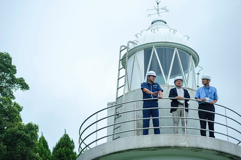 灯台から富山湾を眺める安部龍太郎さん。写真右が和田学さん。