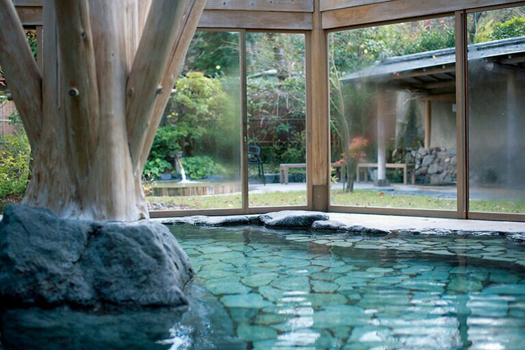 【亀の井別荘】自然石を用いた大浴場「草の湯」の室内風呂。ガラス張りの天井から陽射しがたっぷり注ぐ。Photo: Hiroshi Mizusaki