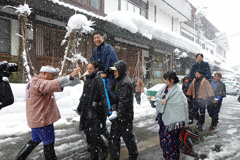 旅館を出発する「むこ」たち。投げられるまでは足を地面につけてはいけないそう。